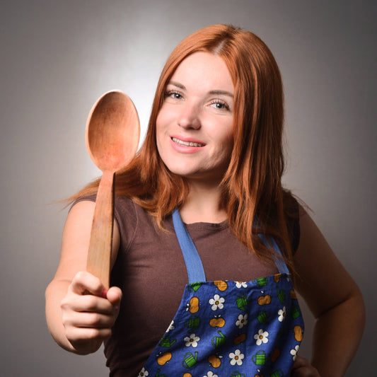 Picture of a smiling girl with red hair proudly holding a hand carved wood spoon. Shop local gifts with LocalWe.